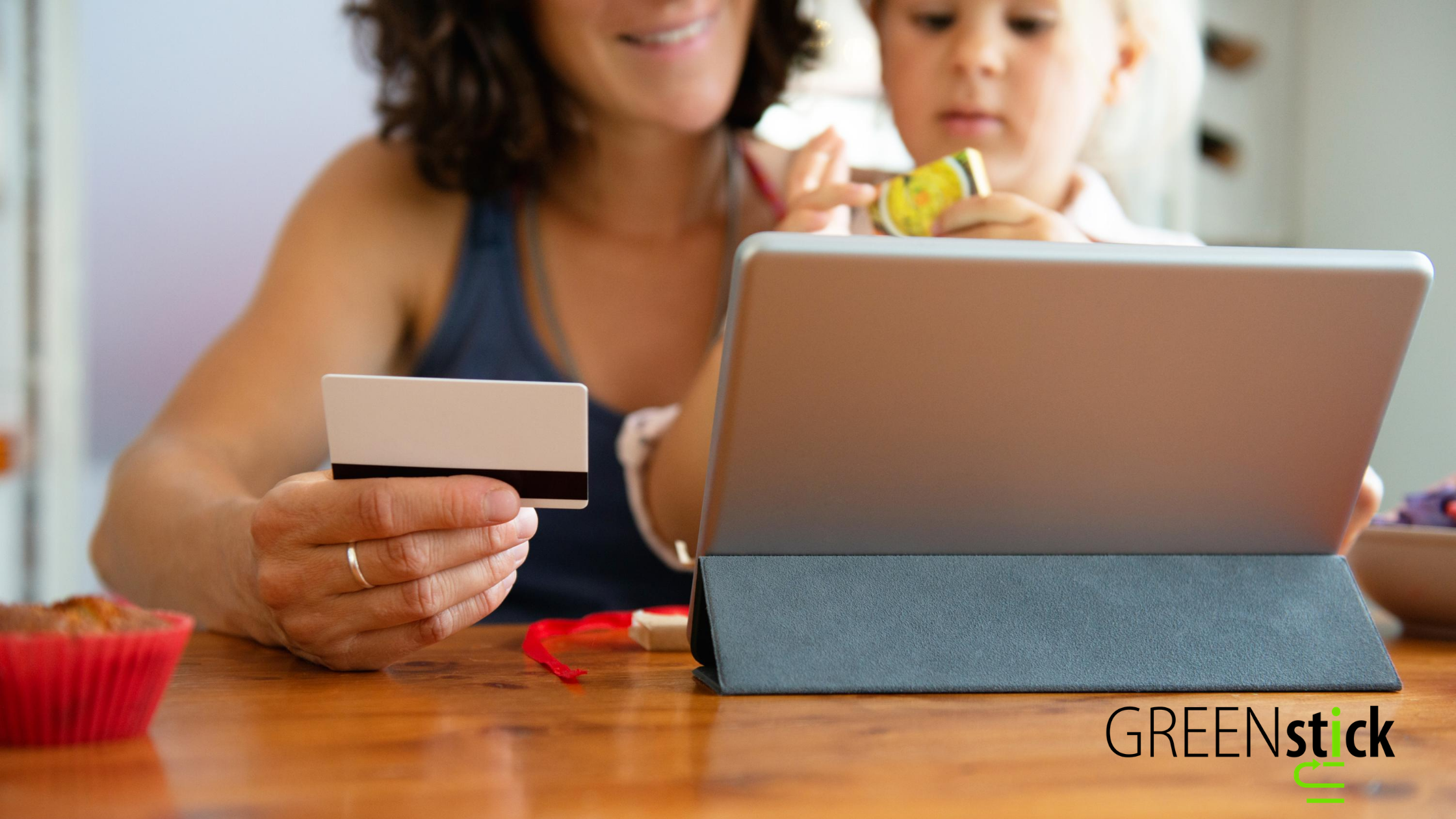 Adult women and baby girl shopping online on an ipad using a business gift card to complete their purchase. 